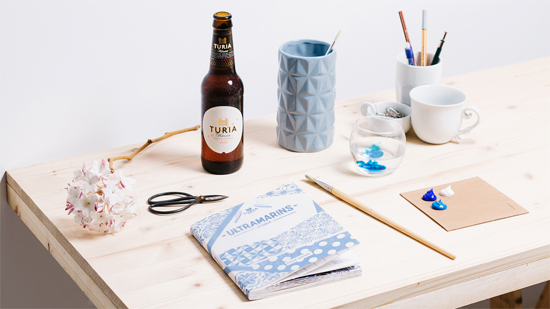 Guía sobre escritorio junto a una cerveza Turia