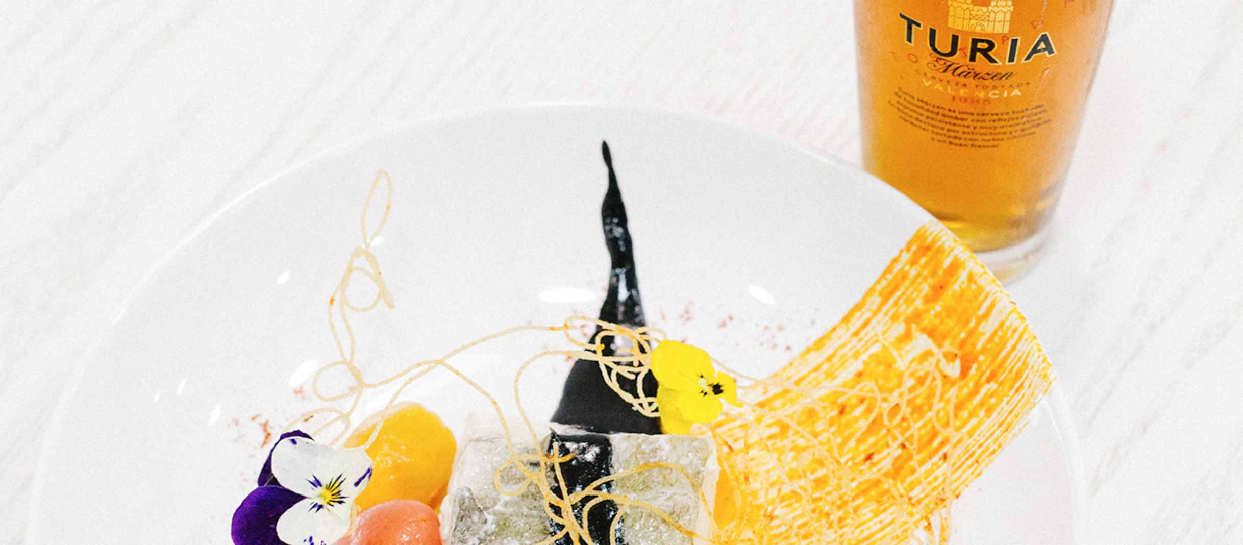 Plato gourmet junto a cerveza Turia